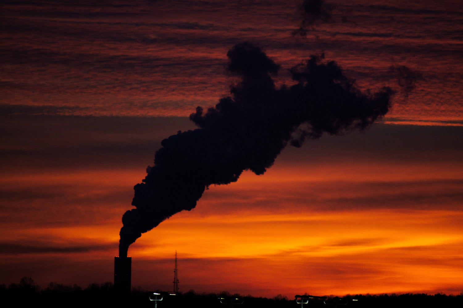the-silhouette-of-a-smoke-plume-from-a-plant-at-sunset